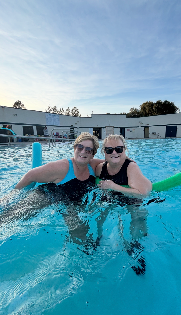 Two Clouds Rest friends smiling together in the pool with aqua noodles