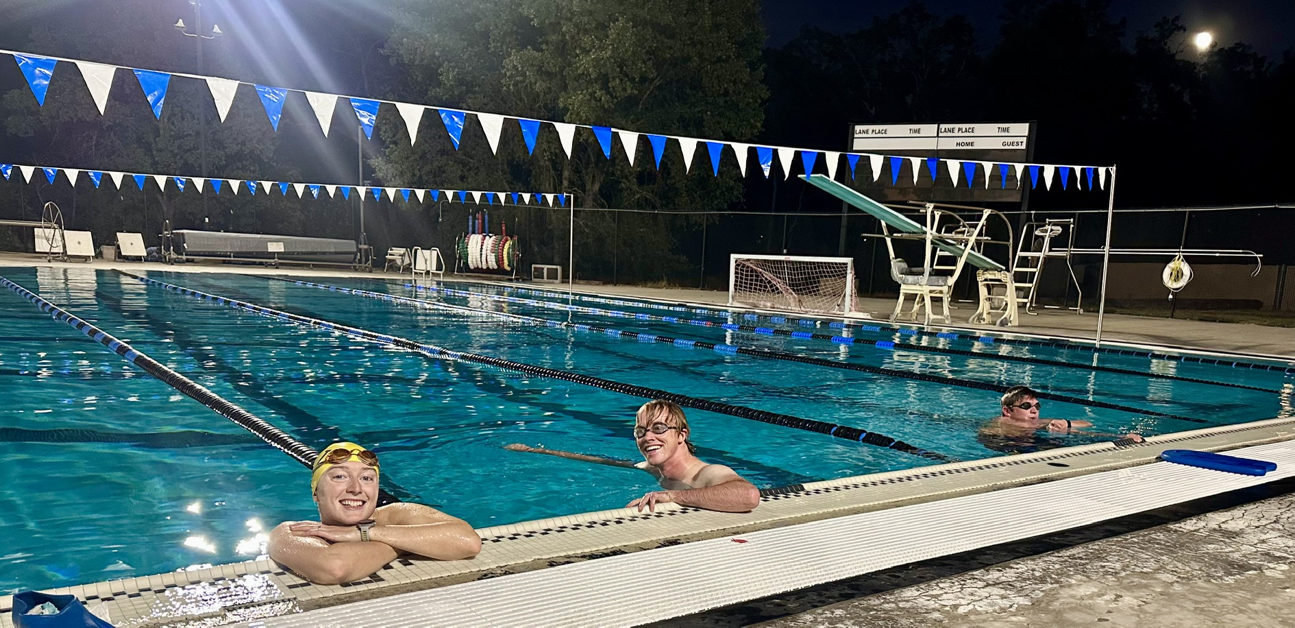 Clouds Rest swimmers smiling together in the illuminated pool at night