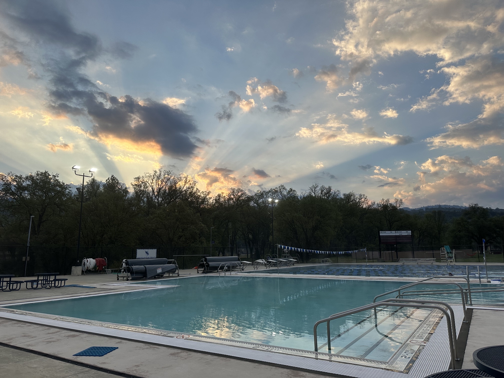 Morning sun rays spreading through clouds above the pool
